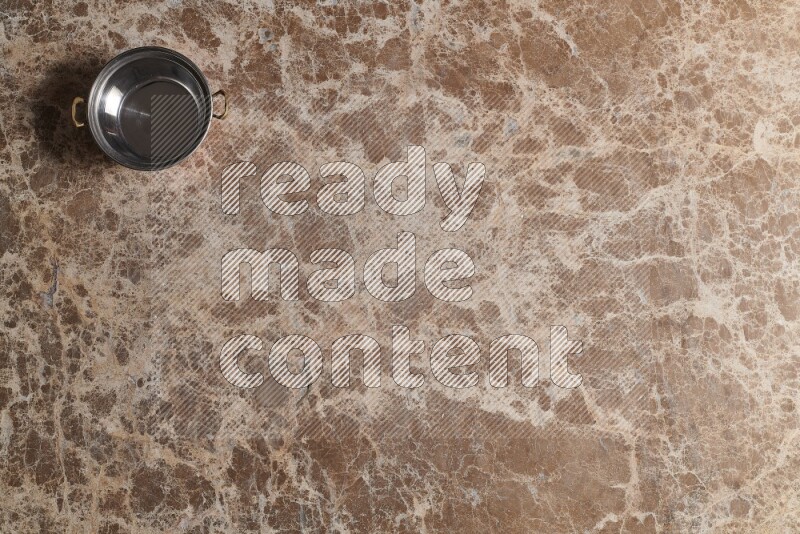 A small copper pot on beige marble background