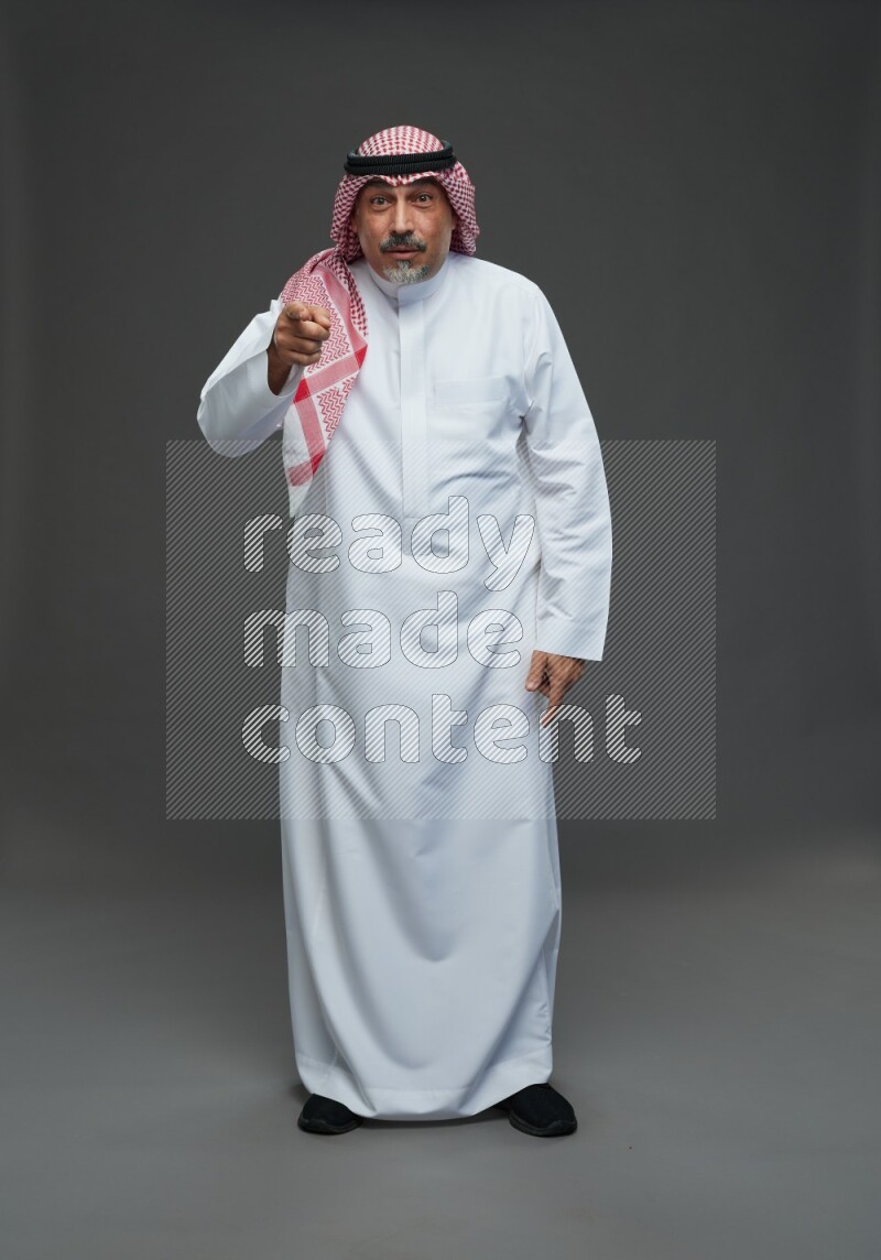 Saudi man with shomag Standing Interacting with the camera on gray background