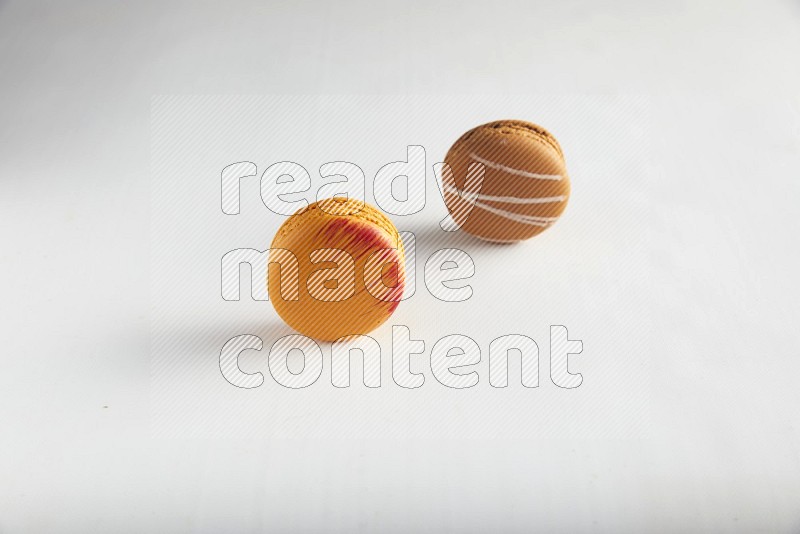 45º Shot of of two assorted Brown Irish Cream, and Orange Exotic macarons on white background