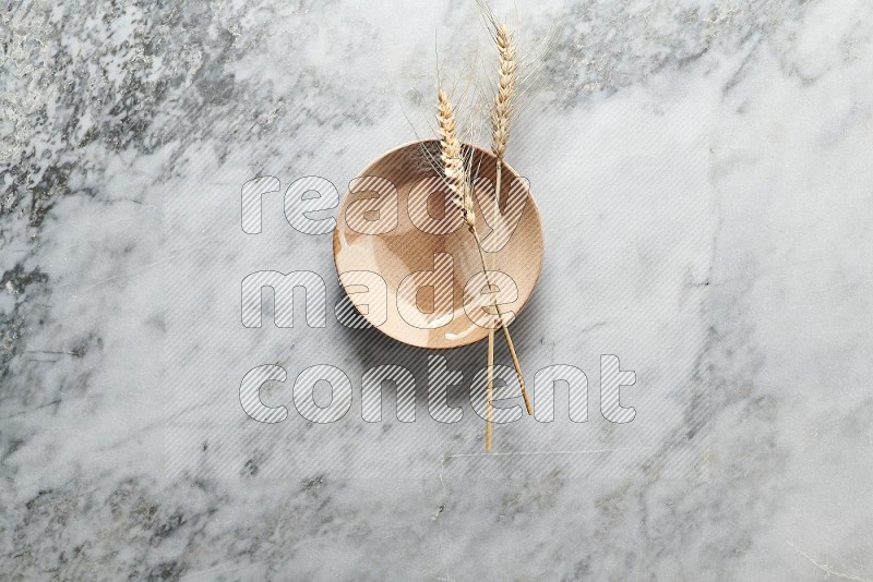 Wheat stalks on Multicolored Pottery Plate on grey marble flooring, Top view