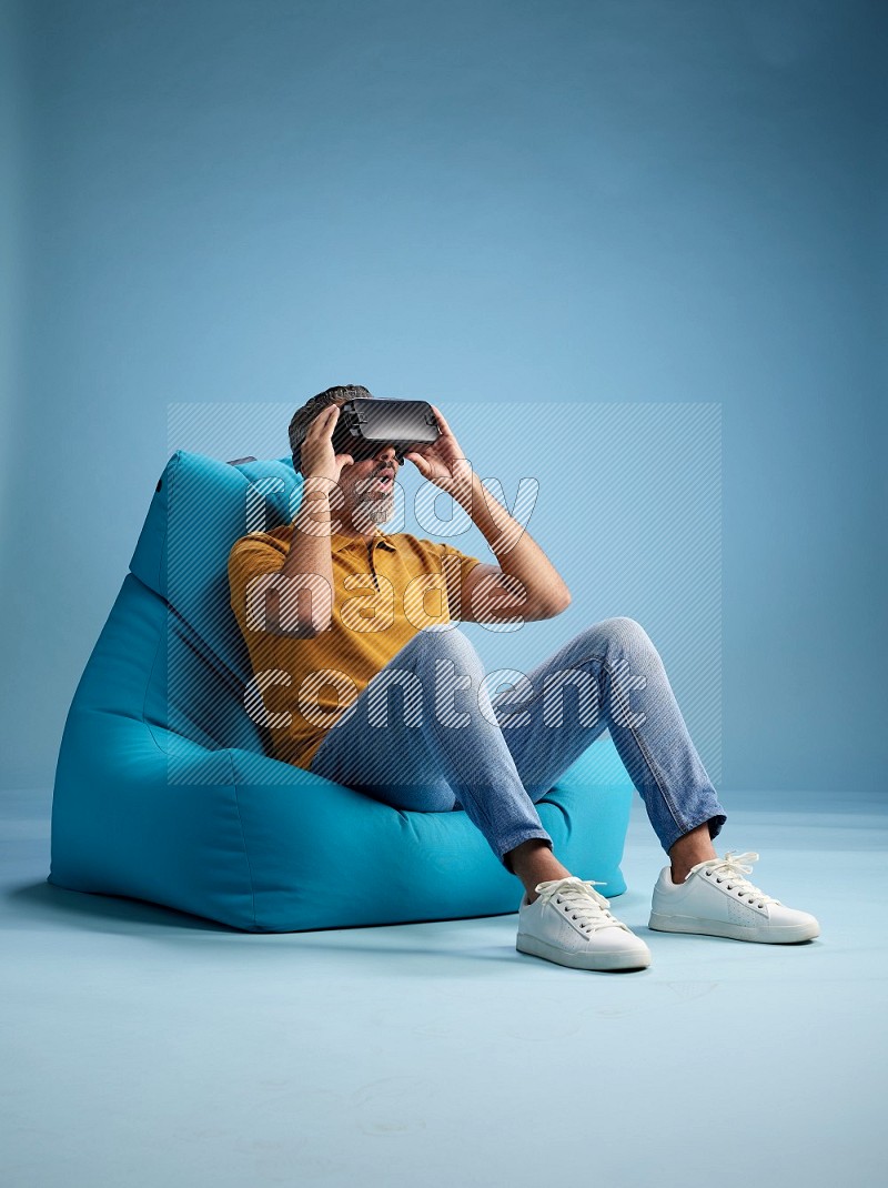 A man sitting on a blue beanbag and gaming with VR