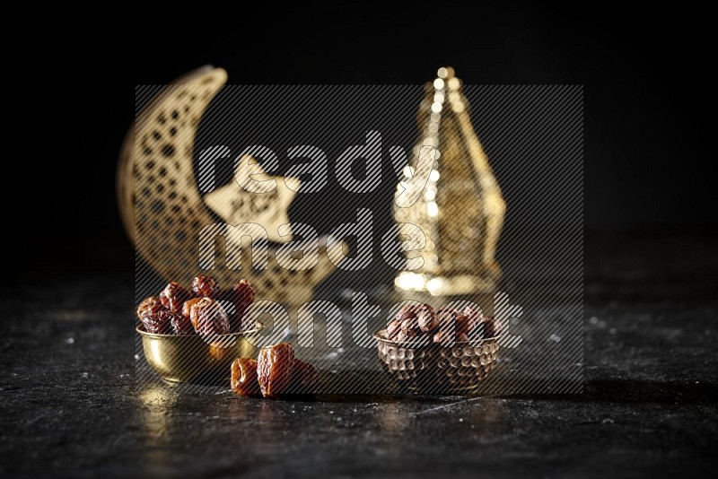 Dates in a metal bowl with hazelnuts beside golden lanterns in a dark setup