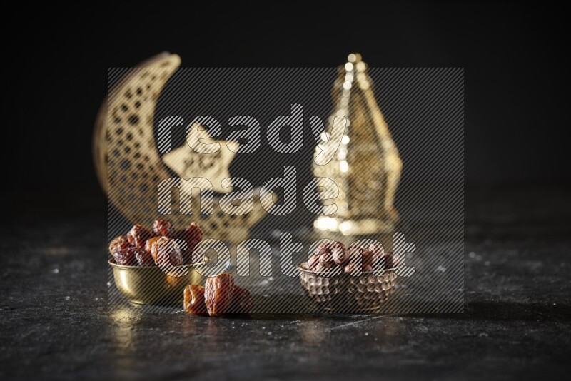 Dates in a metal bowl with hazelnuts beside golden lanterns in a dark setup