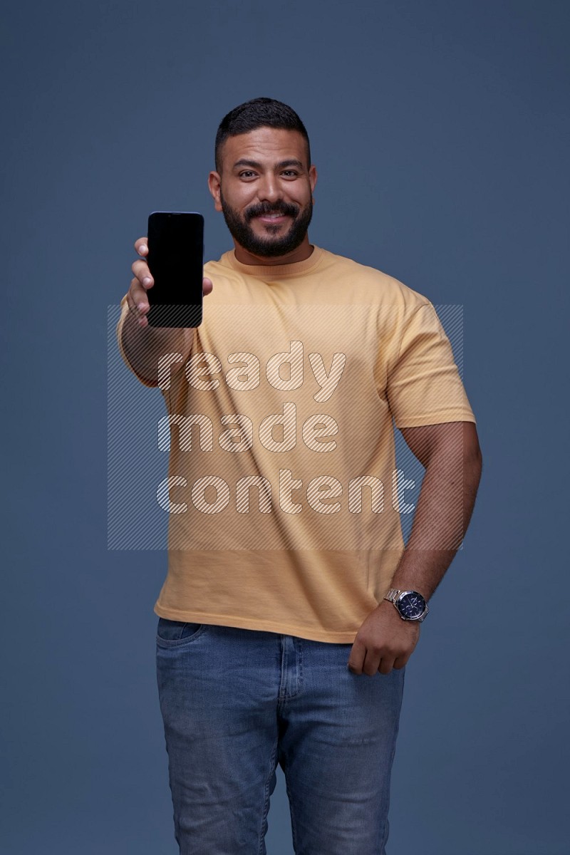 A man Showing His Smart Phone on Blue Background wearing Orange T-shirt