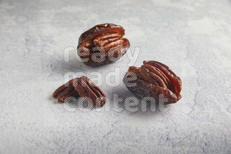 two pecan stuffed madjoul dates on a light grey background