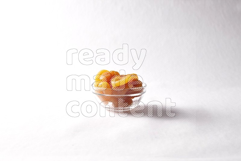 Dried apricots in a glass bowl on white background