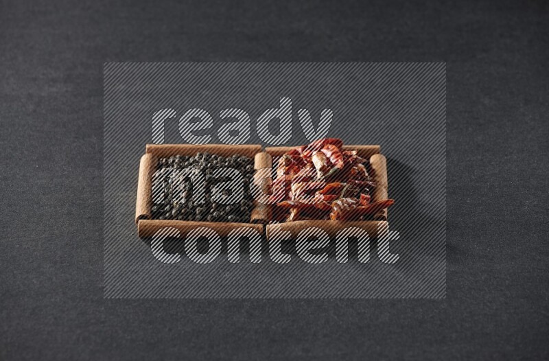 2 squares of cinnamon sticks full of chilis and black peppers on black flooring