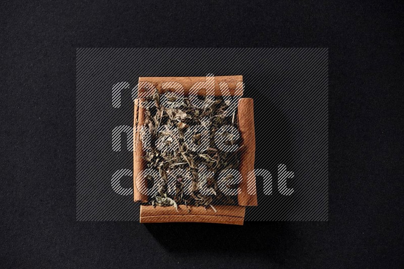 A single square of cinnamon sticks full of dried basil on black flooring