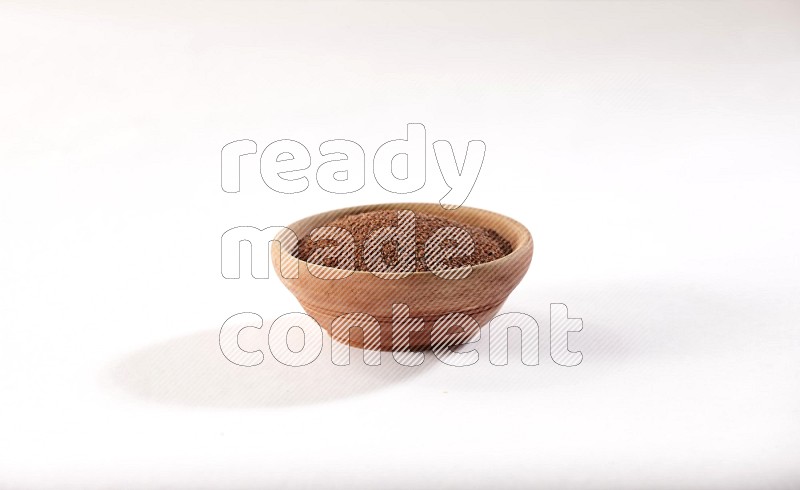 A wooden bowl full of garden cress seeds on a white flooring