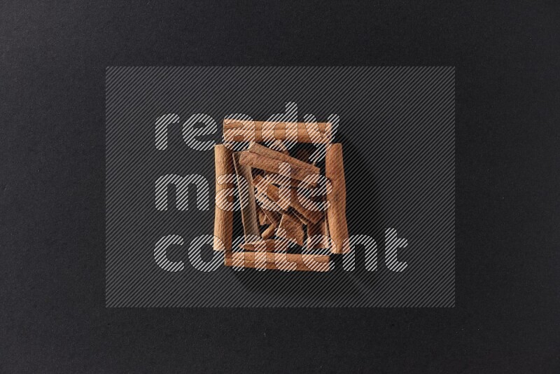 A single square of cinnamon sticks full of cinnamon on black flooring