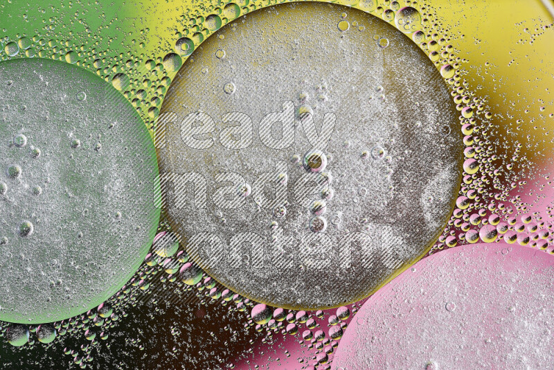 لقطات مقربة لفقاعات من الزيت على سطح الماء باللون الأصفر والأخضر والوردي