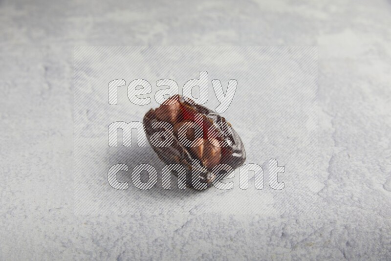 hazelnuts stuffed madjoul date on a light grey background