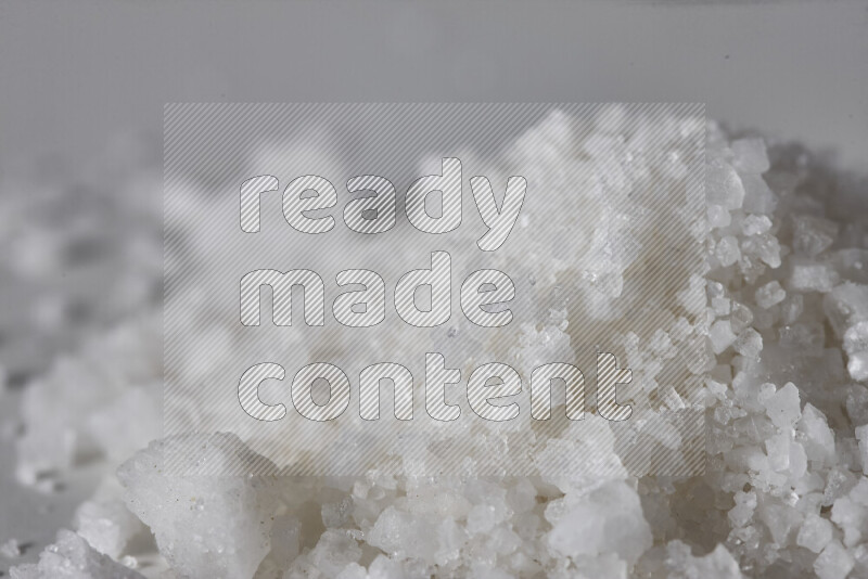 A bunch of coarse sea salt crystals on white background