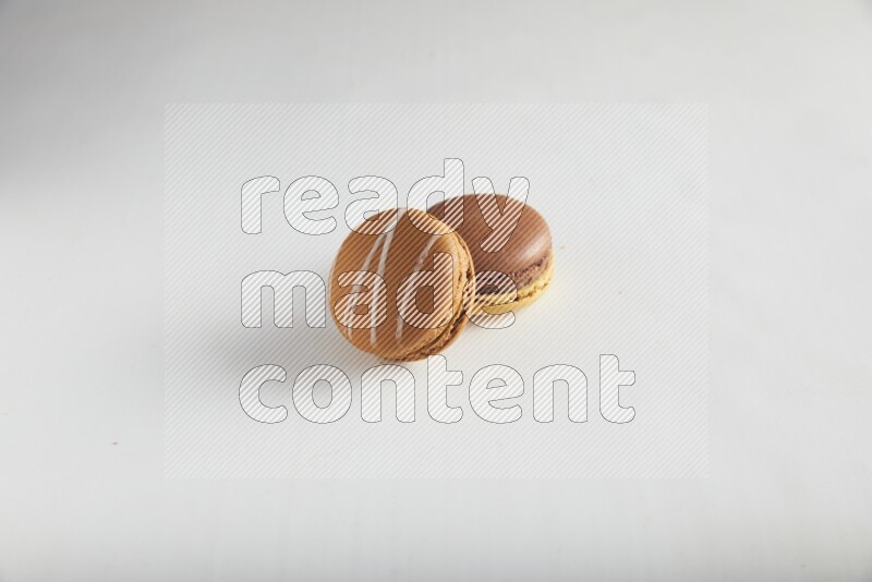 45º Shot of of two assorted Brown Irish Cream, and Yellow, and Brown Chai Latte macarons on white background
