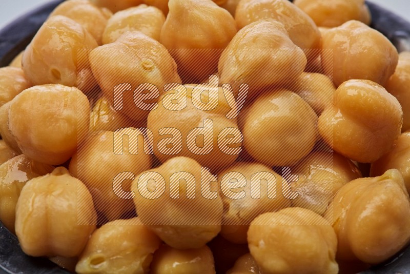 Close up shot of boiled chickpeas in a container on white background