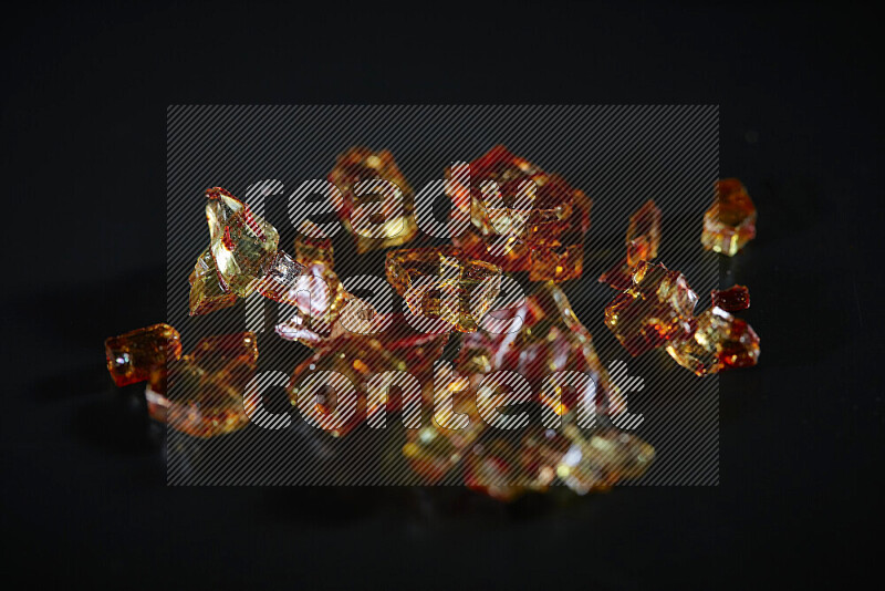 Transparent orange fragments of glass scattered on a black background