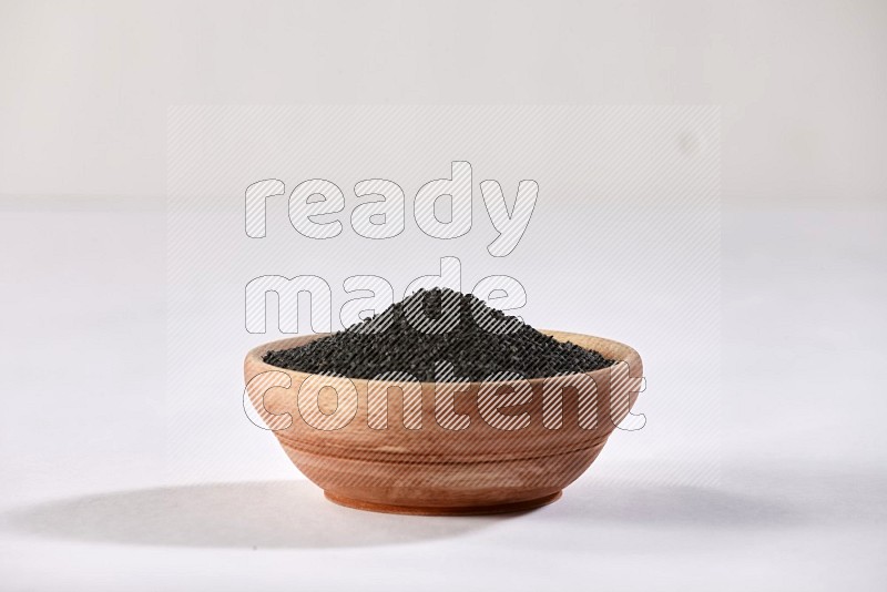 A wooden bowl full of black seeds on a white flooring in different angles