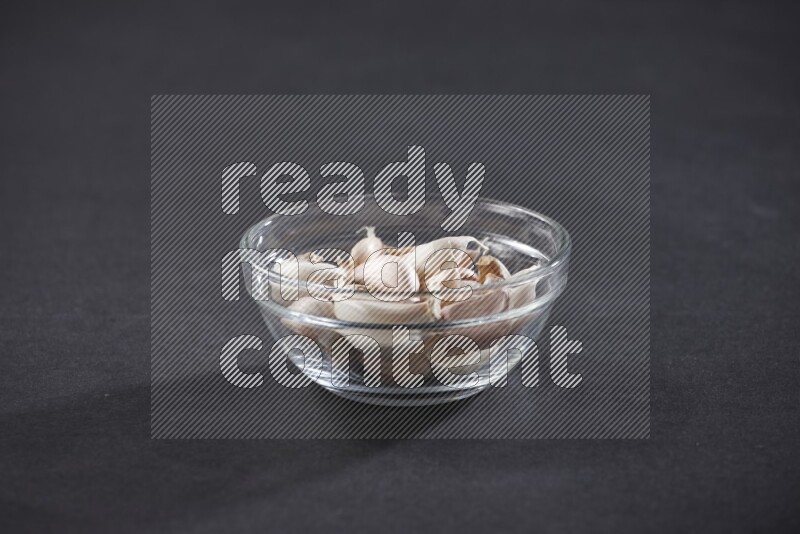 A glass bowl full of garlic cloves on a black flooring