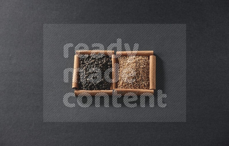 مربعان من أعواد القرفة ممتلئان بحبوب الخردل وحبوب الفلفل الأسود علي خلفية سوداء