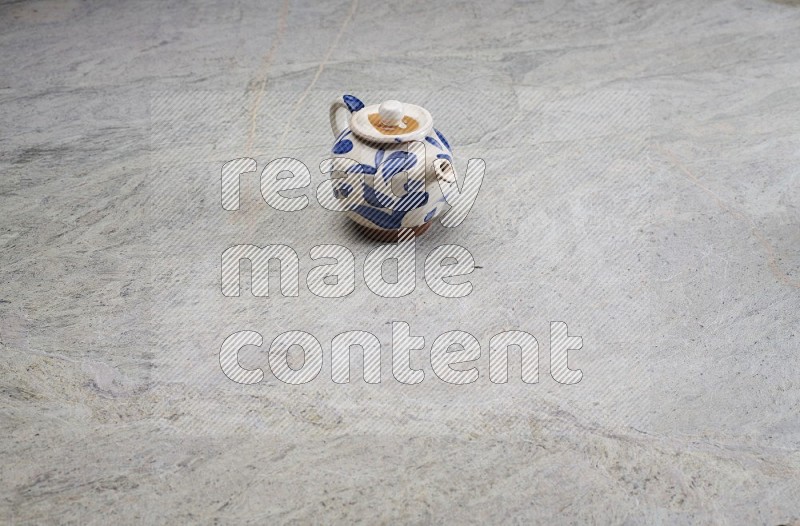 A Pottery Teapot On Grey Marble Flooring