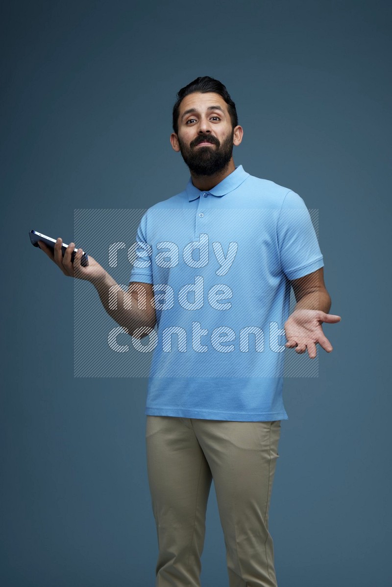 Man posing with a phone in a blue background wearing a Blue shirt