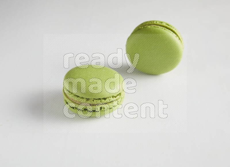 45º Shot of two Green Pistachio macarons on white background