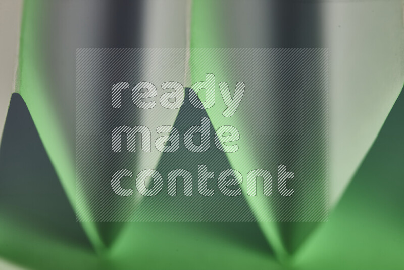 صورة مجردة مقربة تظهر طيات ورقية هندسية حادة بتدرجات اللون الأبيض و الأخضر