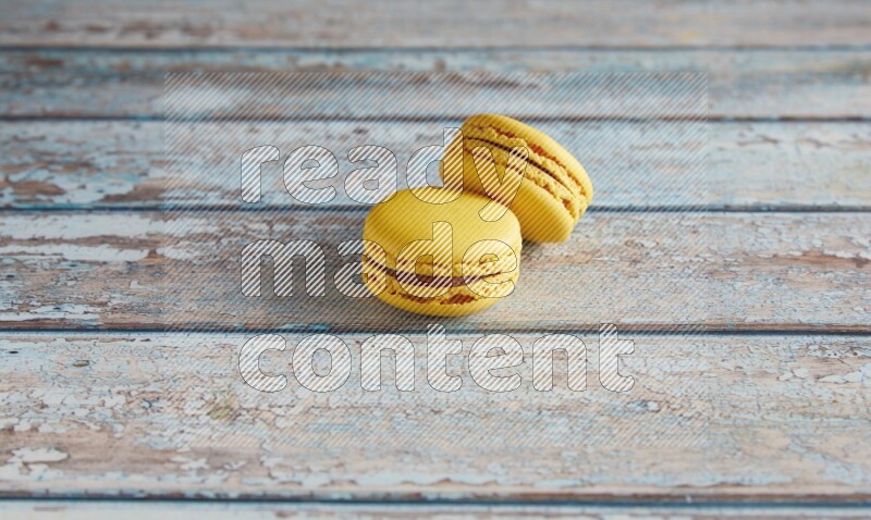 45º Shot of two Yellow Lemon macarons on light blue wooden background