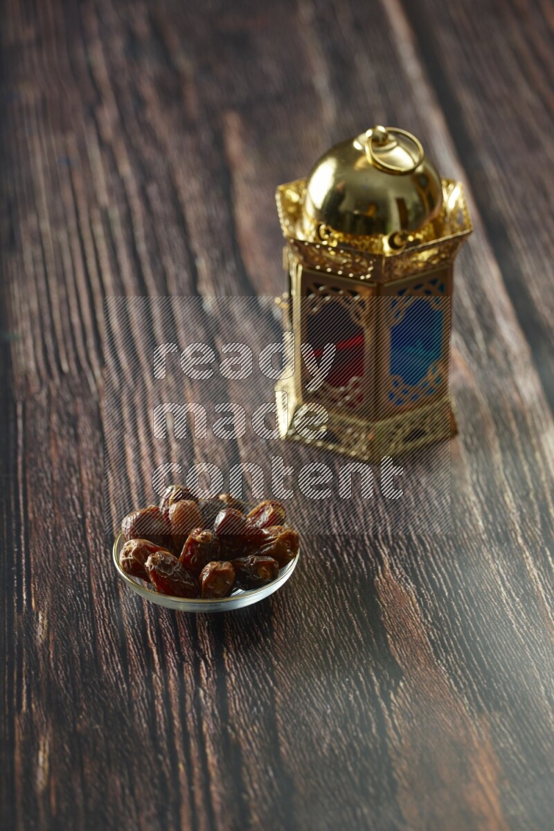 A golden lantern with different drinks, dates, nuts, prayer beads and quran on brown wooden background