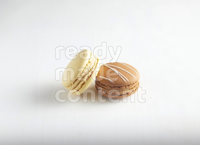 45º Shot of of two assorted Brown Irish Cream, and Yellow Vanilla macarons on white background