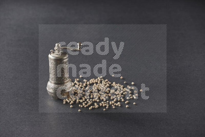 White pepper with a metal pepper grinder on black flooring