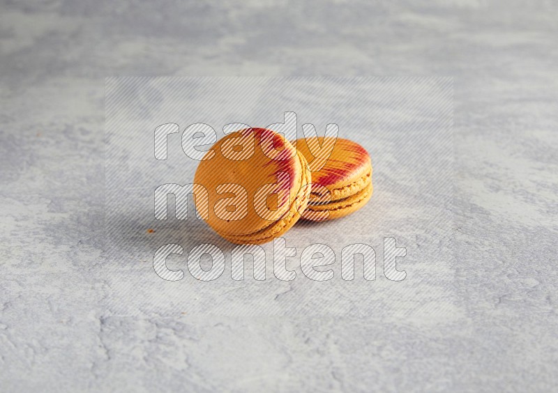 45º Shot of two orange Exotic macarons on white  marble background