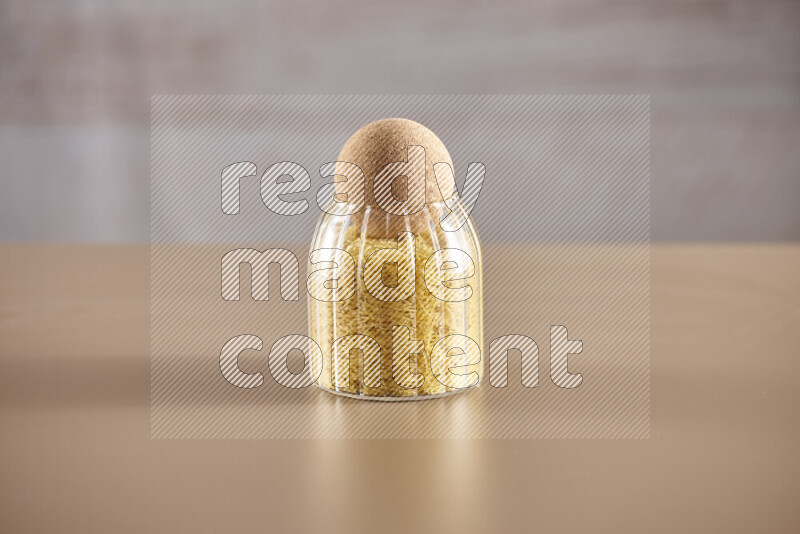 Raw pasta in glass jars on beige background