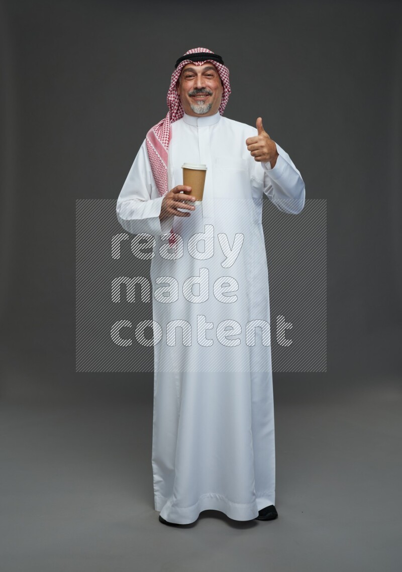 Saudi man with shomag Standing holding paper cup on gray background