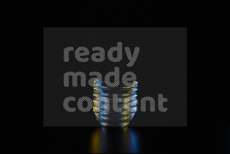 Glassware with rim light in blue and yellow against black background