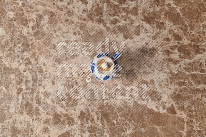 A pottery teapot on beige marble background
