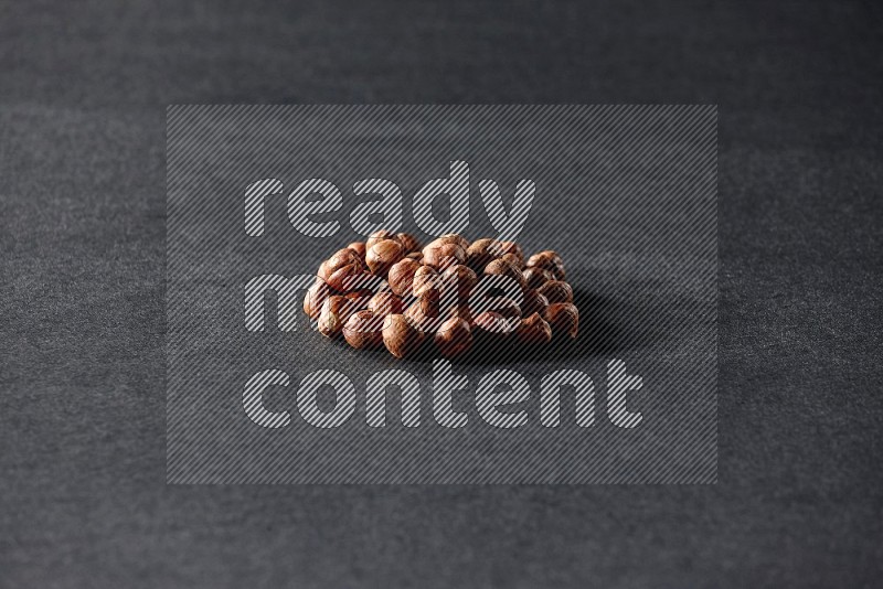 A bunch of peeled hazelnuts on a black background in different angles