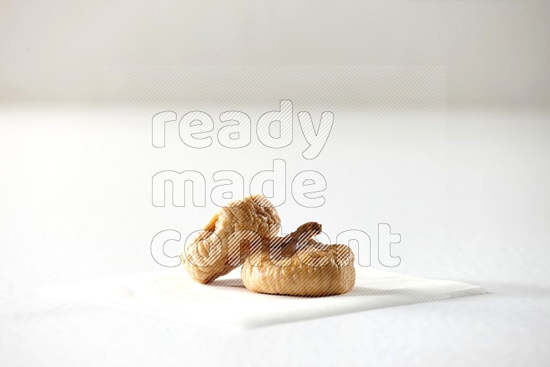 Two dried figs on a piece of paper on a white background in different angles