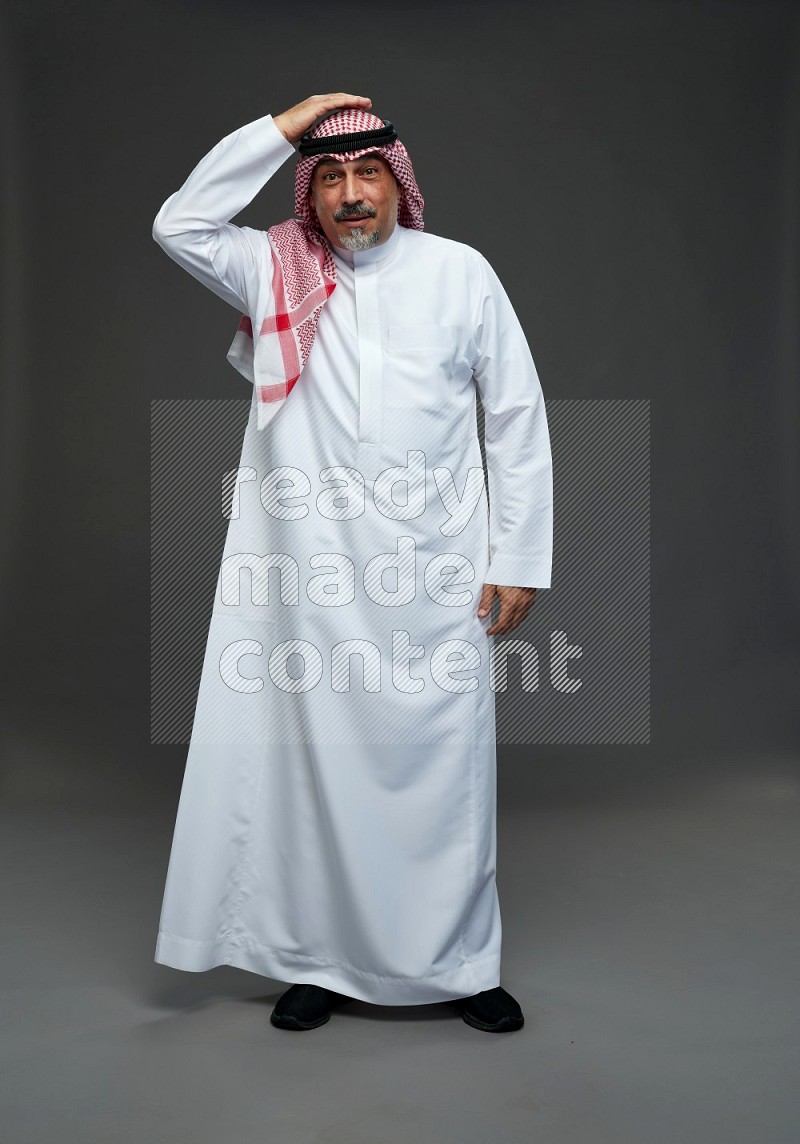 Saudi man with shomag Standing Interacting with the camera on gray background