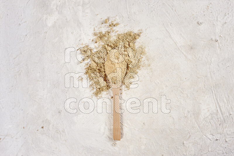 A wooden spoon full of ground ginger powder on white background