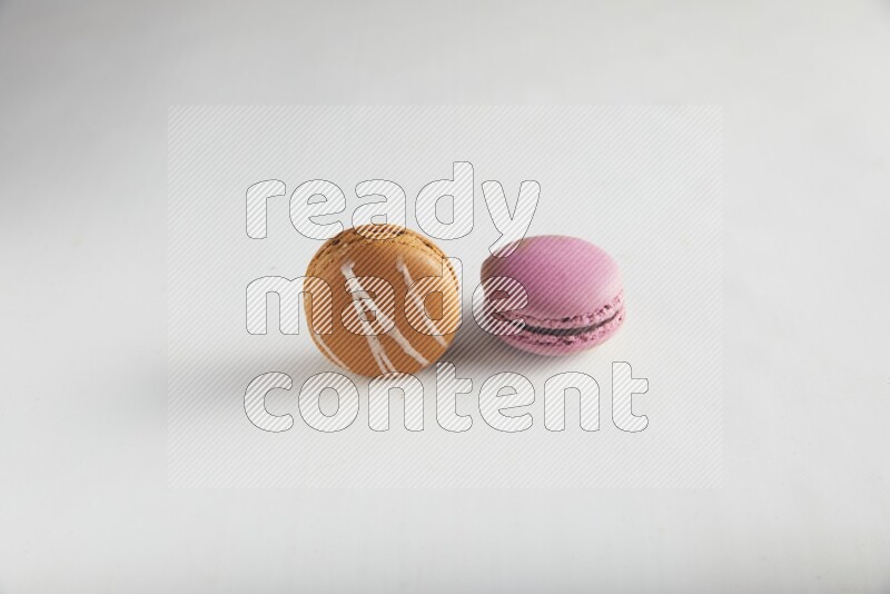45º Shot of of two assorted Brown Irish Cream, and Purple Strawberry macarons on white background