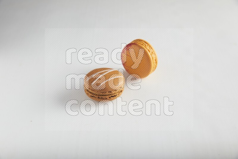 45º Shot of of two assorted Brown Irish Cream, and Orange Exotic macarons on white background
