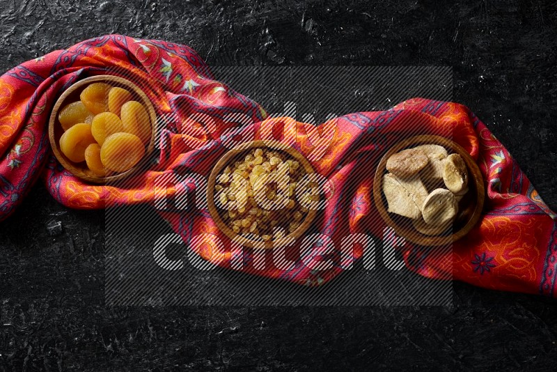 Dried fruits in wooden bowls in a dark setup