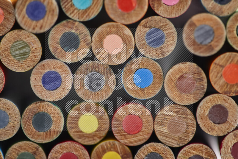 A close-up of the tips of colored pencils arranged in a bundle on white background