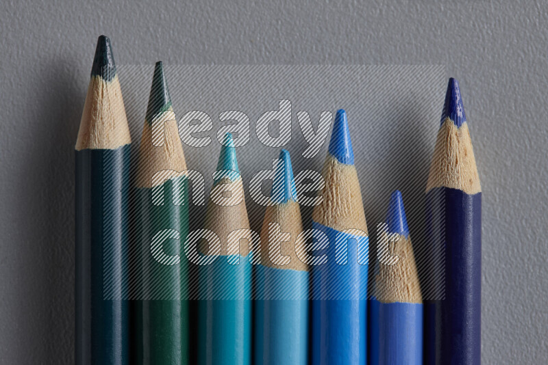 مجموعة من أقلام الرصاص الملونة مرتبة لتعرض تدرجا من الألوان الزرقاء علي خلفية رمادية