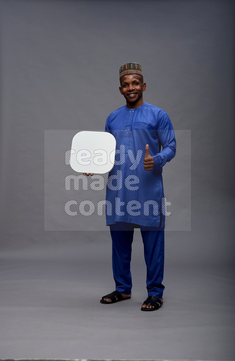 Man wearing Nigerian outfit standing holding social media sign on gray background