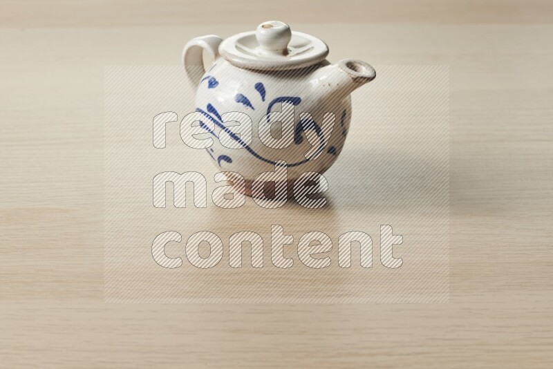 A pottery teapot on light wooden background