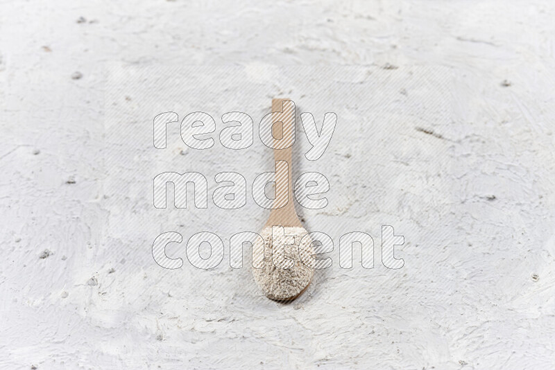 A wooden spoon full of onion powder on white background