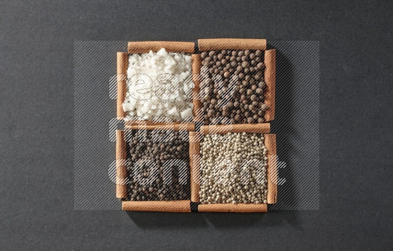 4 squares of cinnamon sticks full of black pepper, white pepper, allspice and white salt on black flooring