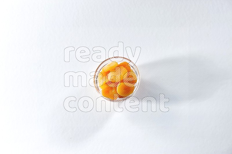 A glass bowl full of dried apricots on a white background in different angles